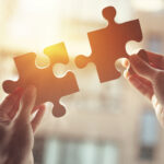 Closeup,Hand,Of,Woman,Connecting,Jigsaw,Puzzle,With,Sunlight,Effect,